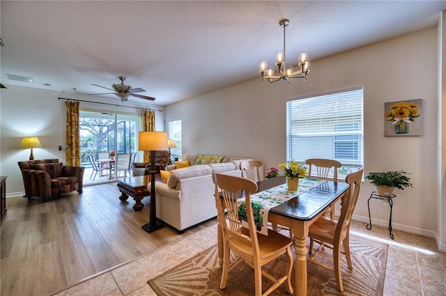 dining room with ceiling fan with notable chandelier, light tile patterned floors, visible vents, and baseboards