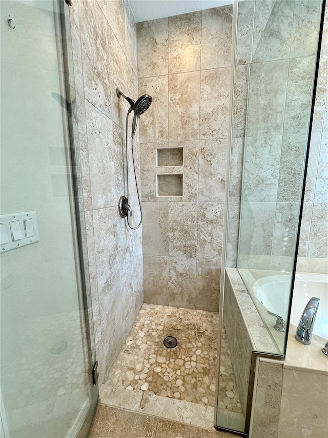 bathroom featuring a garden tub and a shower stall