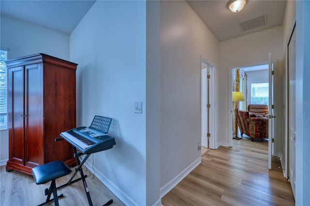 corridor featuring light wood-type flooring, visible vents, and baseboards