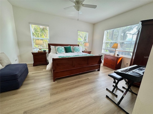 bedroom with light wood-style floors, multiple windows, baseboards, and a ceiling fan