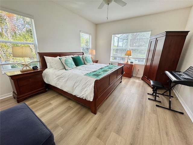 bedroom with light wood-type flooring, a ceiling fan, and baseboards