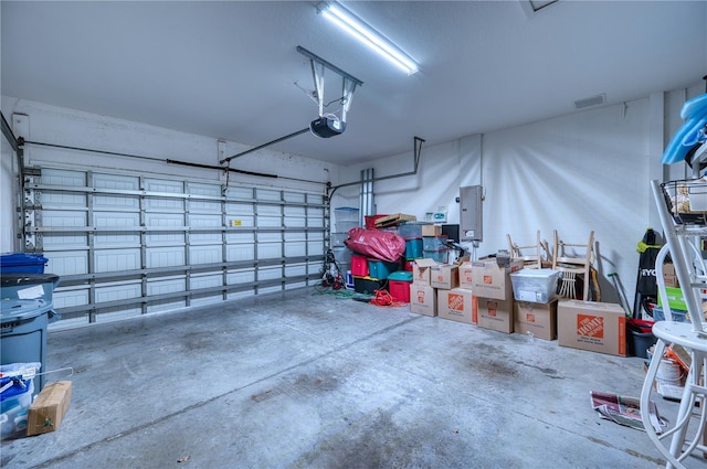 garage featuring a garage door opener, electric panel, and visible vents