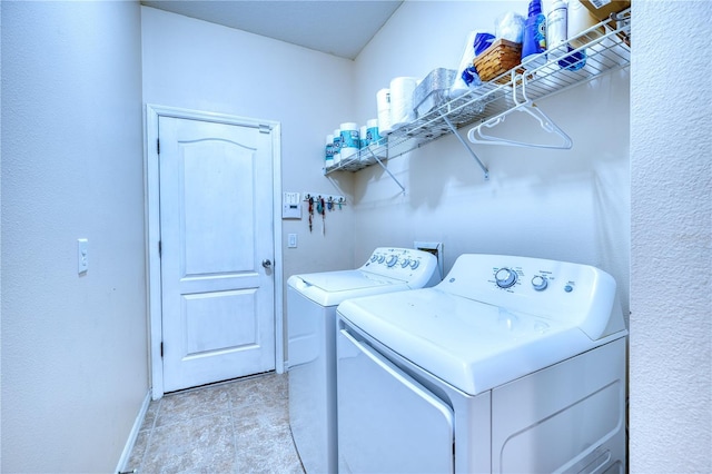 laundry area featuring light tile patterned floors, laundry area, washing machine and clothes dryer, and baseboards