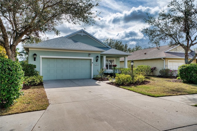 ranch-style house with a porch, an attached garage, a shingled roof, driveway, and stucco siding