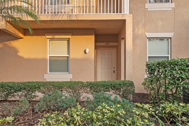 entrance to property with a balcony and stucco siding