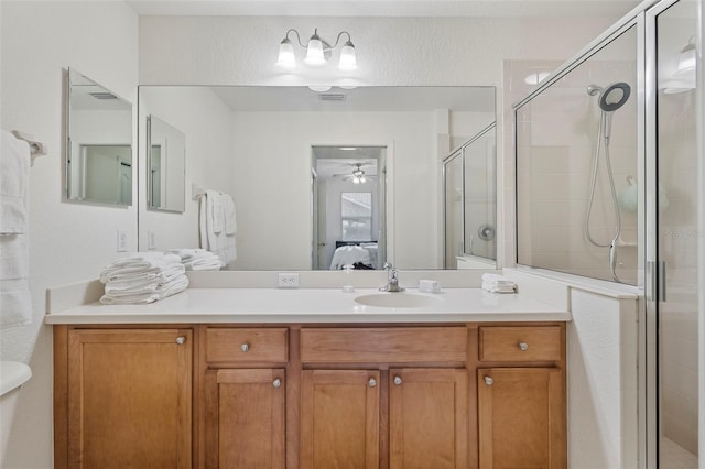 ensuite bathroom featuring a ceiling fan, a shower stall, ensuite bath, and vanity