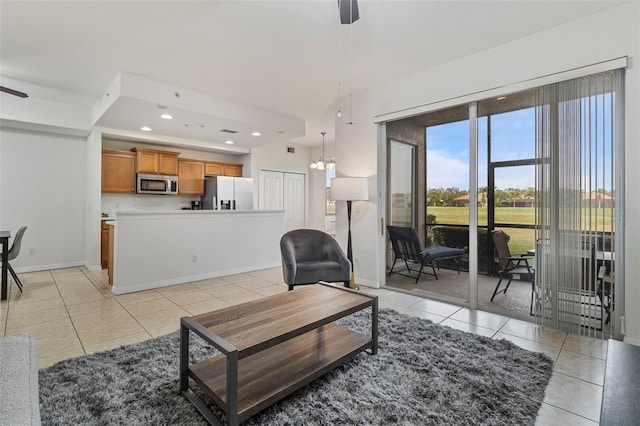 living area with recessed lighting, baseboards, light tile patterned flooring, and ceiling fan with notable chandelier