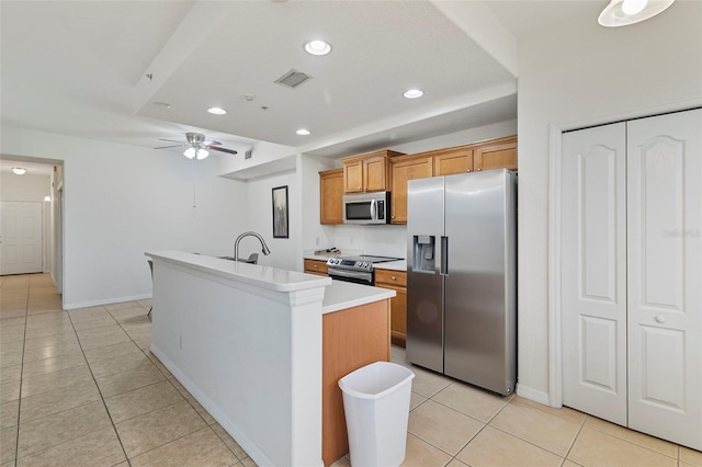 kitchen featuring stainless steel appliances, visible vents, brown cabinetry, a kitchen island with sink, and light tile patterned flooring