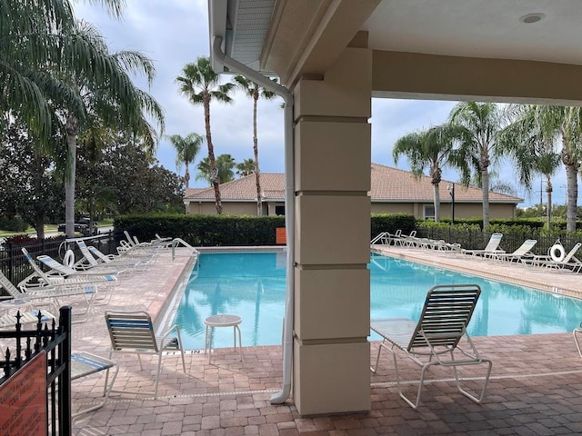 community pool with a patio area and fence