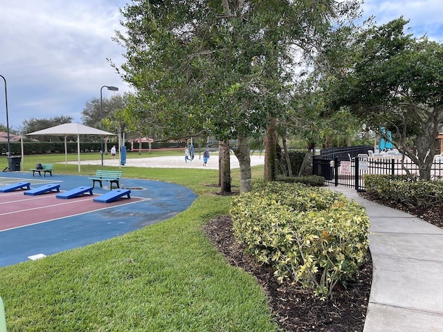 view of community with a lawn, volleyball court, and fence