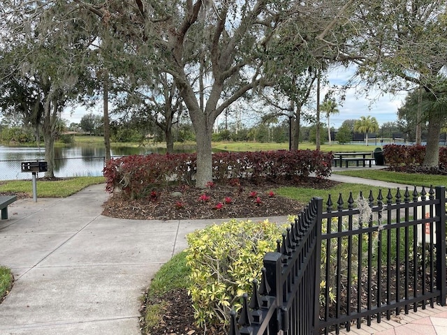 view of home's community with a water view, fence, and a lawn