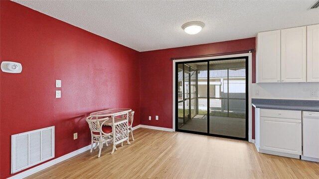 interior space featuring light wood-style floors, visible vents, a textured ceiling, and baseboards