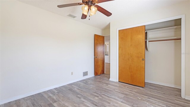 unfurnished bedroom with light wood-type flooring, baseboards, visible vents, and a closet