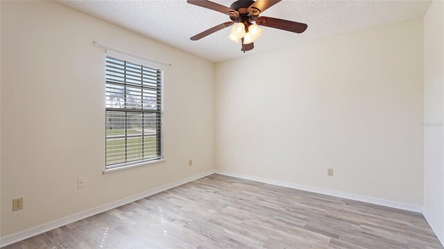 empty room featuring light wood-style floors, a ceiling fan, baseboards, and a textured ceiling