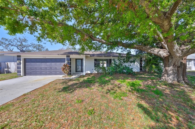 single story home featuring an attached garage, a front lawn, concrete driveway, and stucco siding