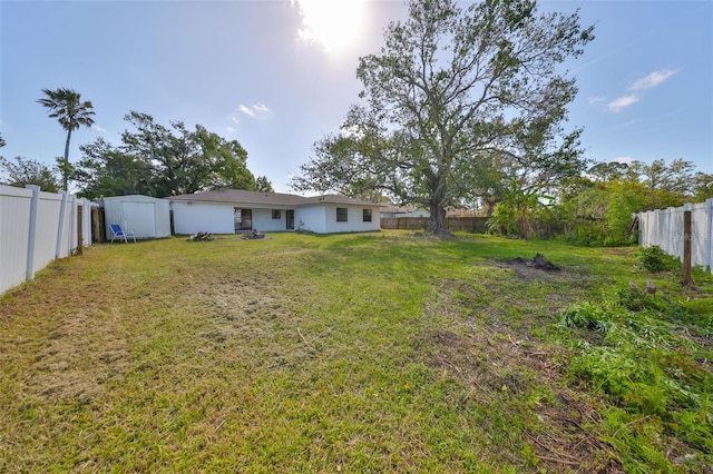 view of yard with a shed, a fenced backyard, and an outbuilding