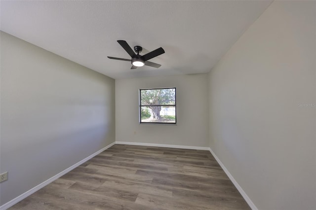 spare room featuring ceiling fan, baseboards, and wood finished floors