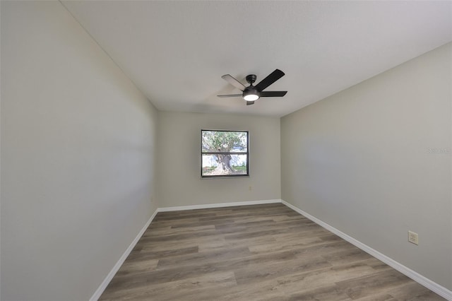 empty room featuring a ceiling fan, baseboards, and wood finished floors