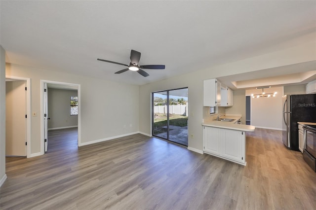 kitchen featuring white cabinets, baseboards, light countertops, and wood finished floors