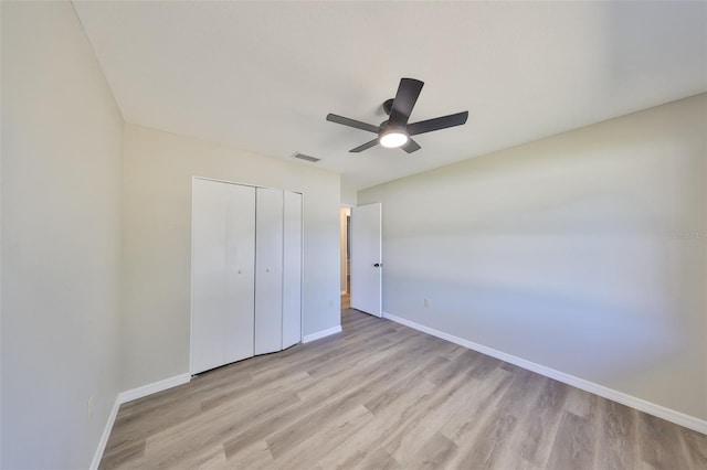 unfurnished bedroom featuring baseboards, a closet, visible vents, and light wood-style floors