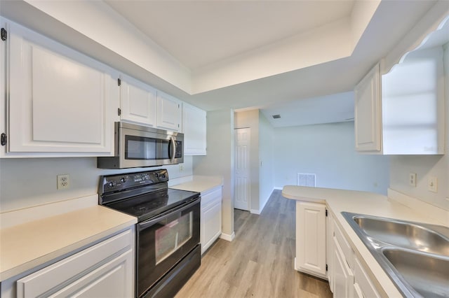 kitchen featuring a sink, stainless steel microwave, white cabinets, and black range with electric stovetop