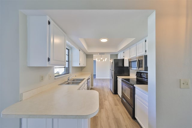 kitchen featuring a chandelier, a sink, white cabinetry, appliances with stainless steel finishes, and a raised ceiling