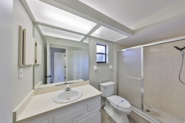 full bath featuring wood finished floors, a shower stall, toilet, and vanity