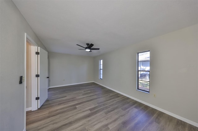 empty room with a ceiling fan, dark wood-style flooring, and baseboards