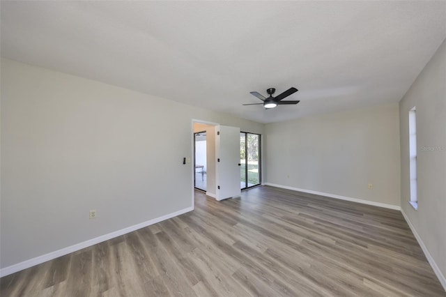 spare room with wood finished floors, a ceiling fan, and baseboards