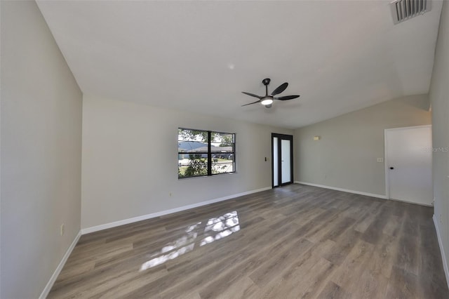 spare room featuring vaulted ceiling, wood finished floors, visible vents, and baseboards