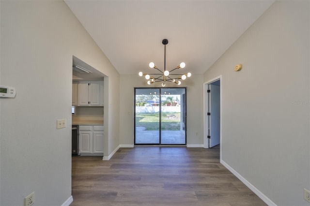 unfurnished dining area featuring a chandelier, vaulted ceiling, wood finished floors, and baseboards