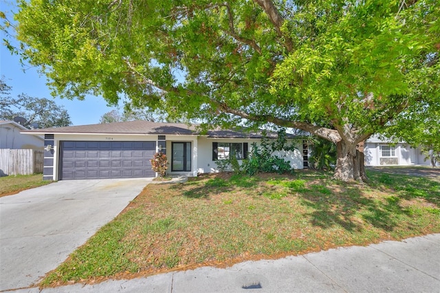 ranch-style home featuring a front lawn, driveway, an attached garage, and fence