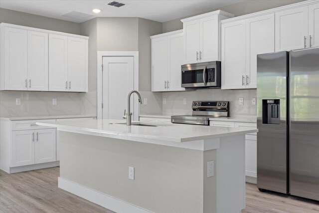 kitchen with stainless steel appliances, a sink, light countertops, and white cabinetry