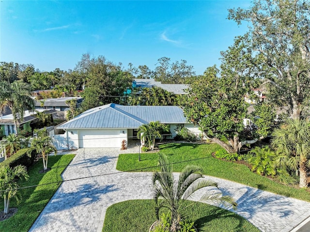 view of front of house featuring a garage, metal roof, decorative driveway, and a front yard