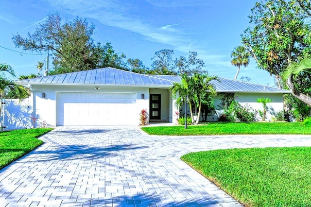 single story home with metal roof, a garage, decorative driveway, stucco siding, and a front lawn