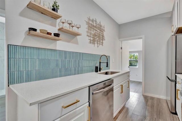 kitchen with a sink, white cabinetry, light countertops, appliances with stainless steel finishes, and open shelves