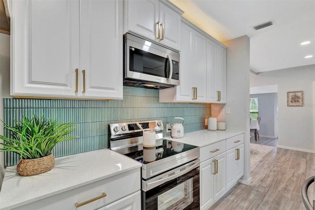 kitchen featuring light stone countertops, visible vents, white cabinetry, and stainless steel appliances