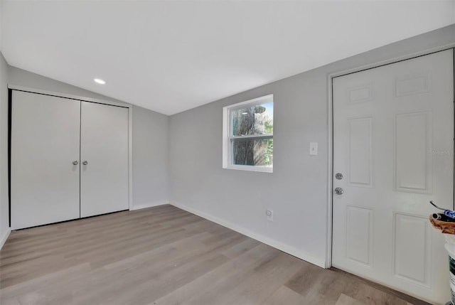 entryway featuring light wood finished floors, baseboards, and vaulted ceiling