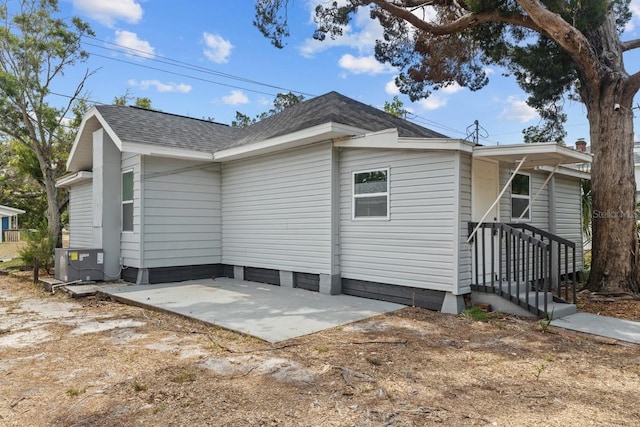 view of home's exterior featuring central AC unit, a patio, and a shingled roof