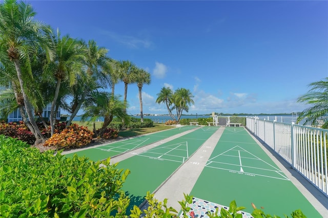 surrounding community featuring a water view, fence, and shuffleboard