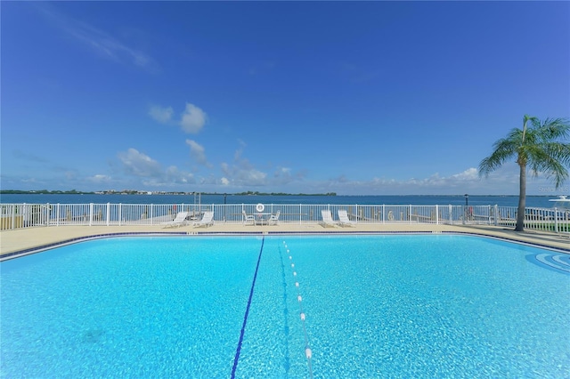 community pool with a water view and fence