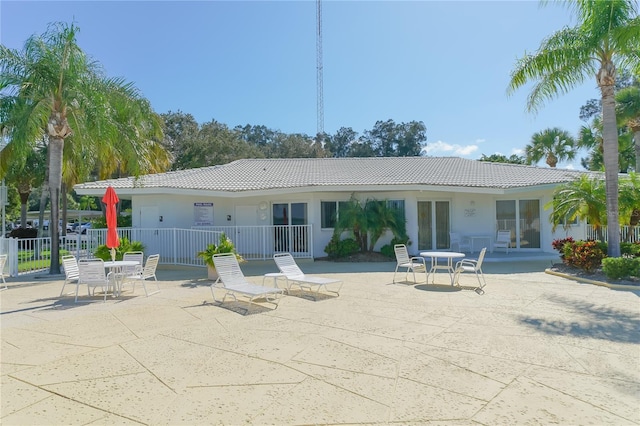 back of property featuring stucco siding, fence, a patio, and a tiled roof