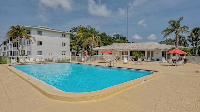 community pool with fence and a patio area