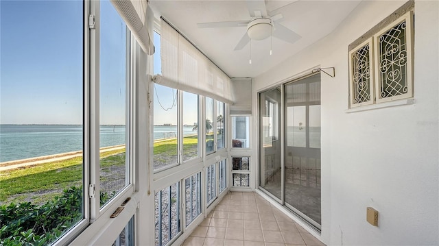 unfurnished sunroom featuring a ceiling fan and a water view
