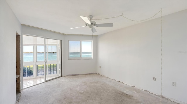 unfurnished room with a water view, ceiling fan, and concrete flooring