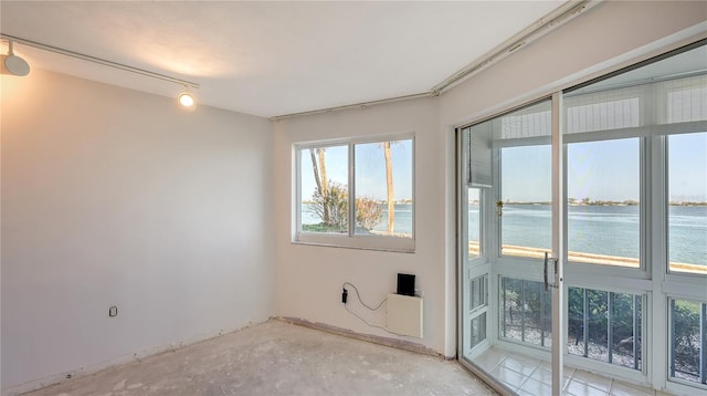spare room featuring rail lighting and a water view