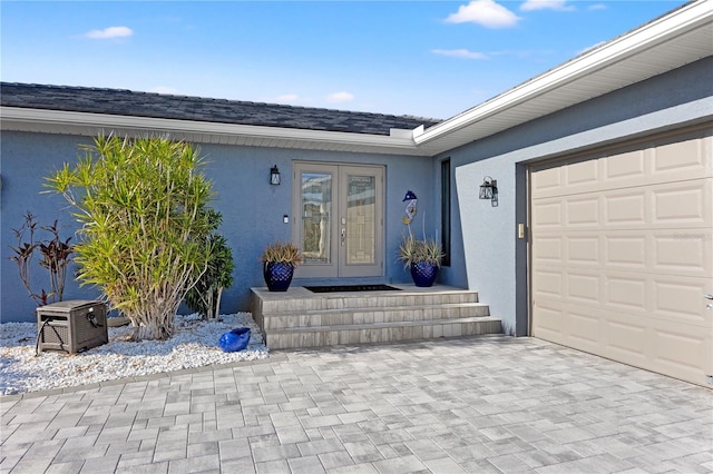 doorway to property with an attached garage, stucco siding, and french doors