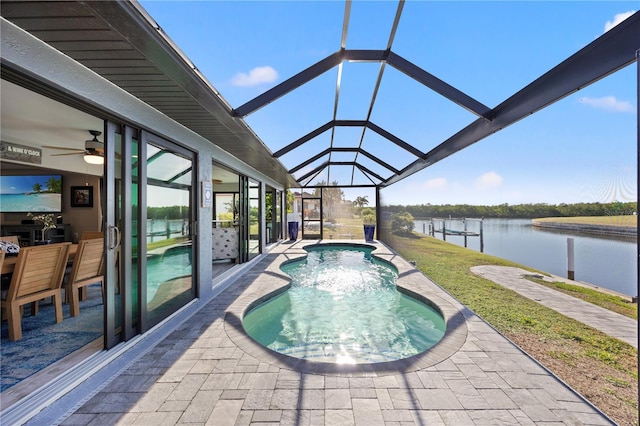 pool featuring glass enclosure, a water view, ceiling fan, and a patio