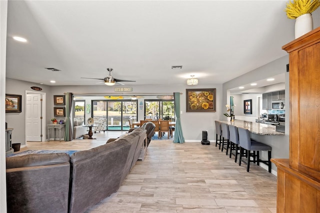 living area featuring baseboards, visible vents, ceiling fan, light wood-style floors, and recessed lighting