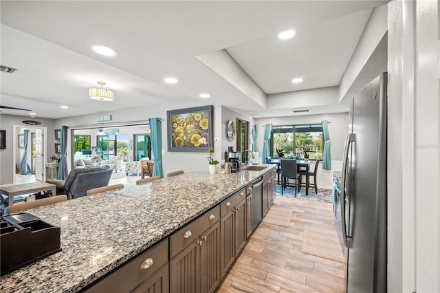 kitchen with stainless steel appliances, light stone counters, plenty of natural light, and wood tiled floor